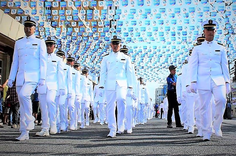 Seafarers marching while wearing type A all white uniform.