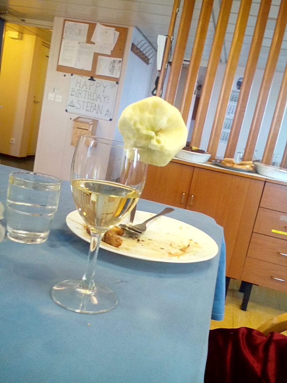 An empty plat and a wine with an apple on the side inside the mess hall.