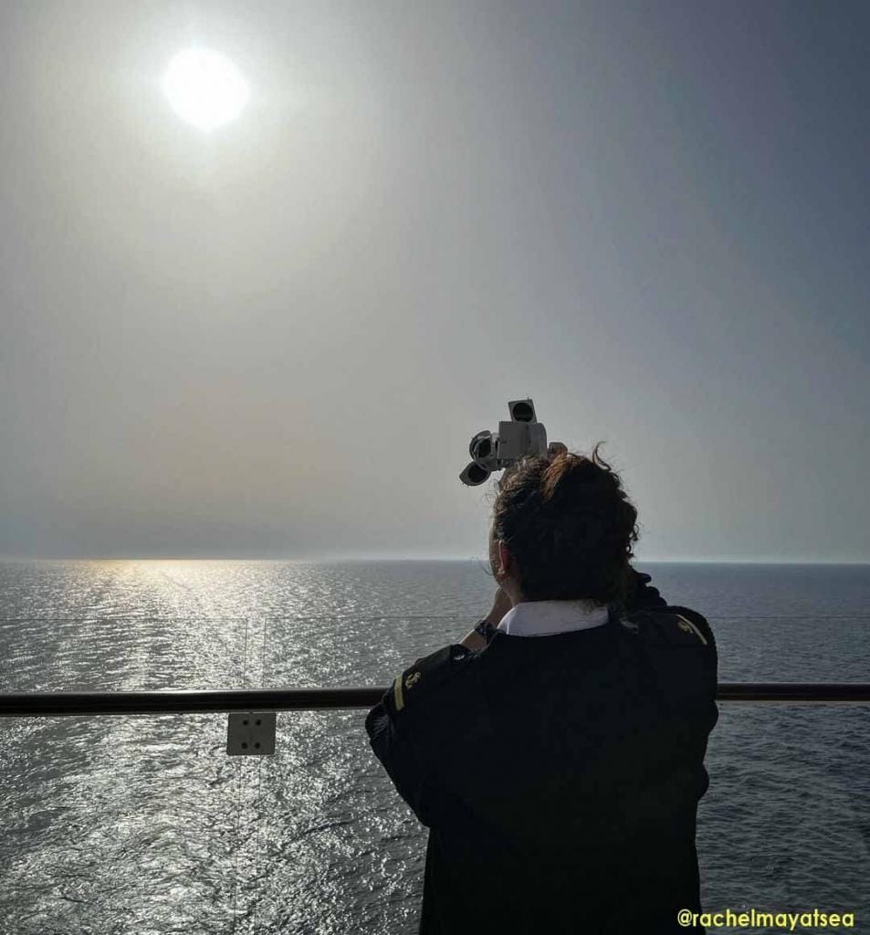 A seawoman taking the altitude of the sun using a sextant behind the vessel. This is oldest method of position fixing in marine navigation.