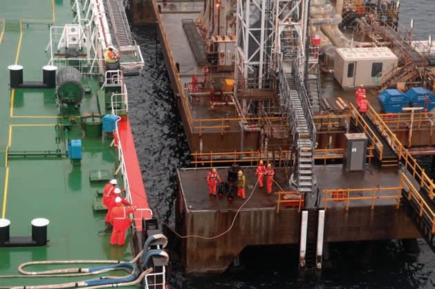 The ship's crew conducting mooring operations with the help of the shore personnel.