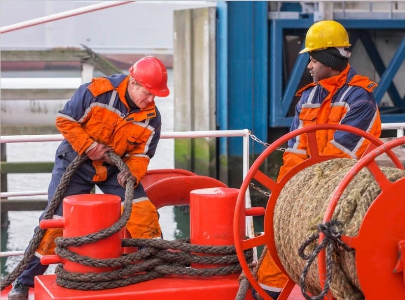 Two crew securing the loose rope aft into the bitts using the figure of eight during mooring.
