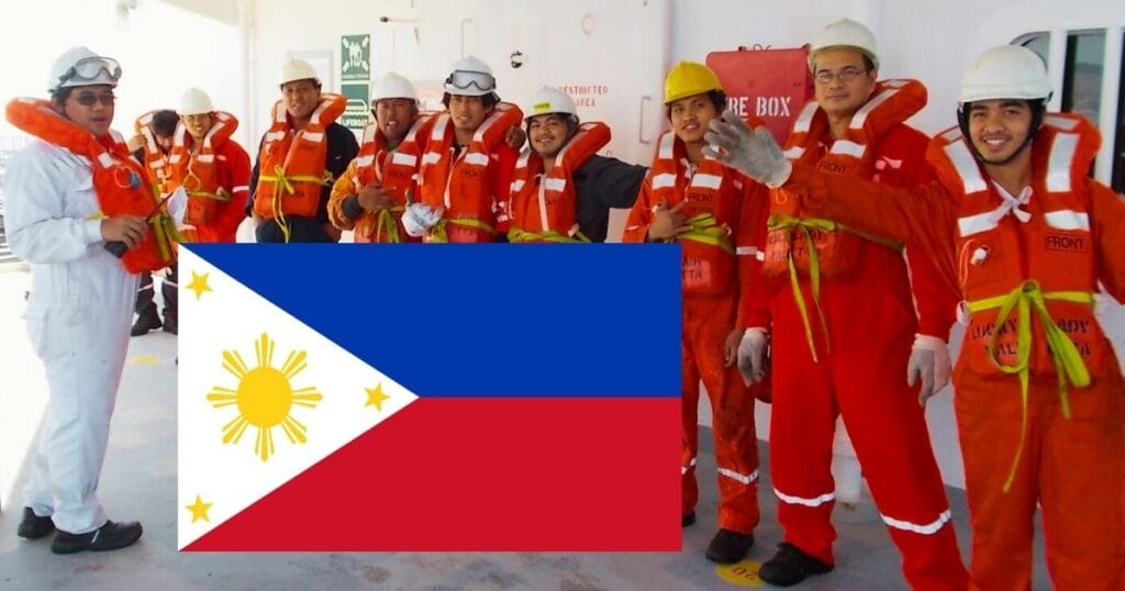 Filipino seafarers wearing orange coverall and the Chief Mate wearing white. A Philippine flag is at the foreground.